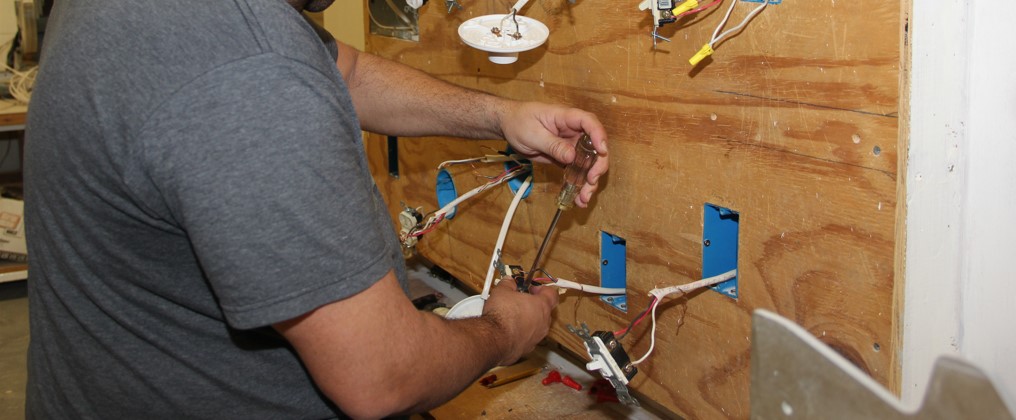 Student installing electrical wiring into electrical outlets.